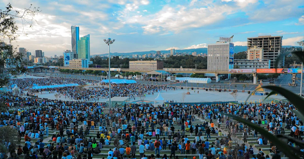 A busy street scene in Addis Ababa with people and buildings under a blue sky.