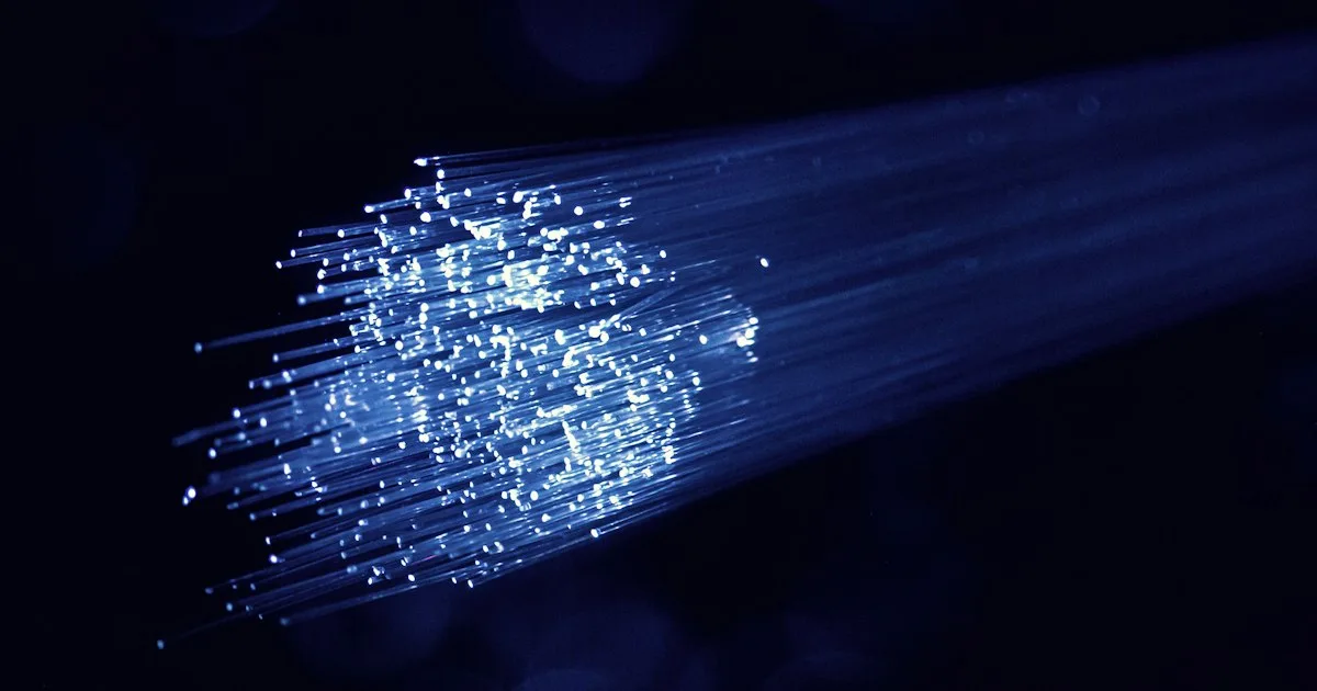 A bundle of glowing optical fibres against a dark background.